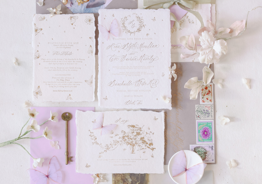 handmade paper wedding stationery flatlay with letterpressed hand illustrated crests, butterflies and florals depicting Scotland